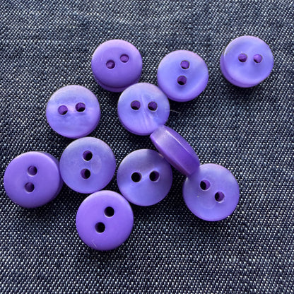 Purple two-hole plastic tablet shirt buttons on denim
