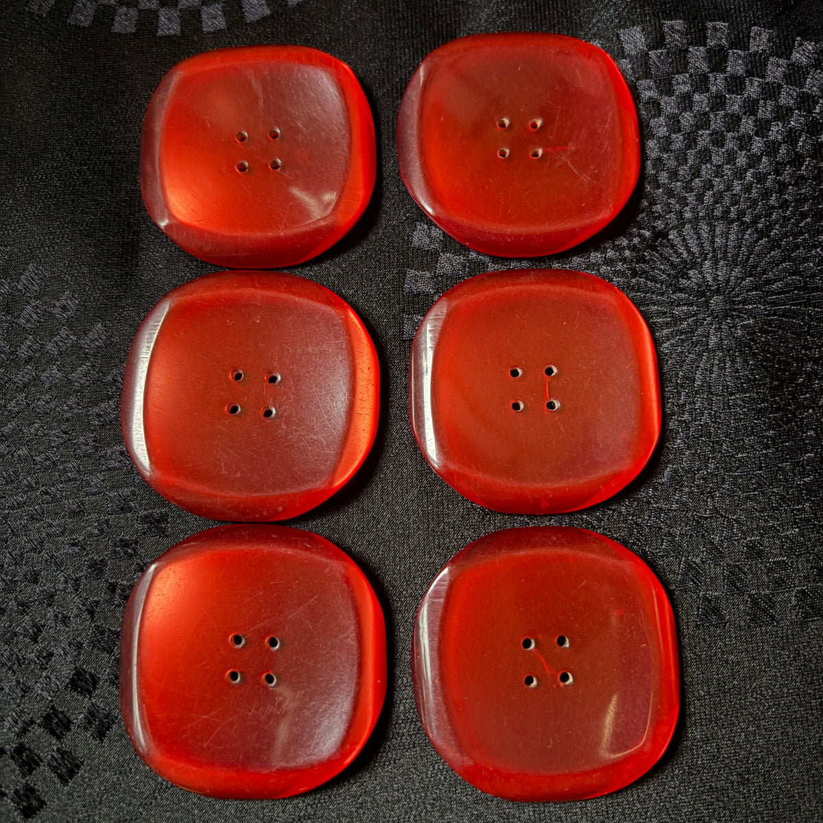 Square red glass buttons with rounded corners catching the light