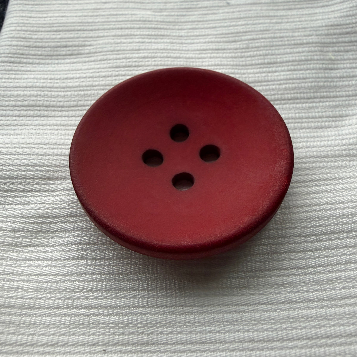 Side view of a red casein button showing its rim and thickness.