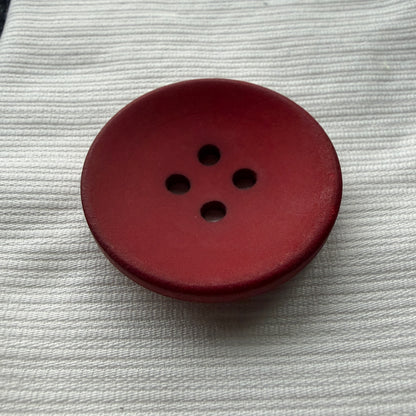 Side view of a red casein button showing its rim and thickness.