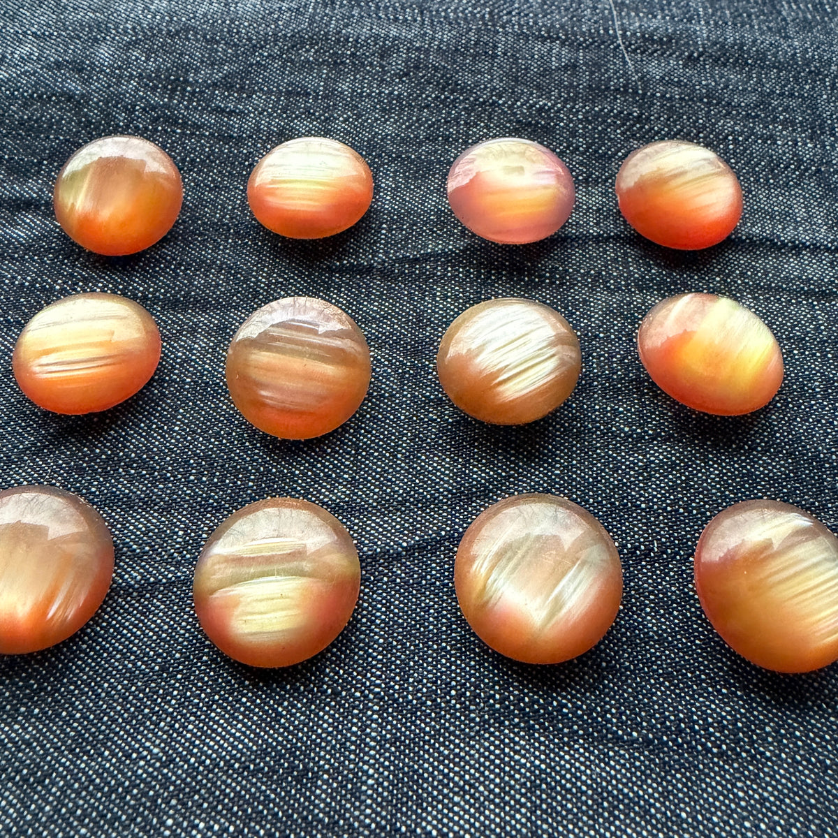 Rose-gold domed casein buttons in rows, showing their colour variation.