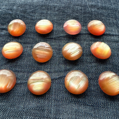 Rose-gold domed casein buttons in rows, showing their colour variation.