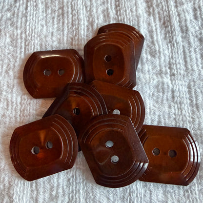 Set of 8 oblong brown casein two-hole buttons with a tiered edge.