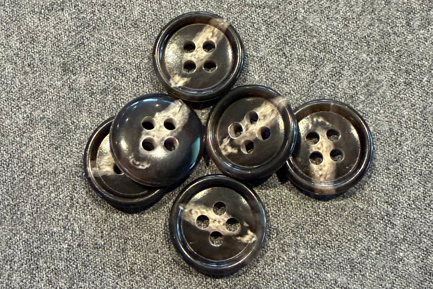 Set of six brown and tan buttons on a textured gray surface