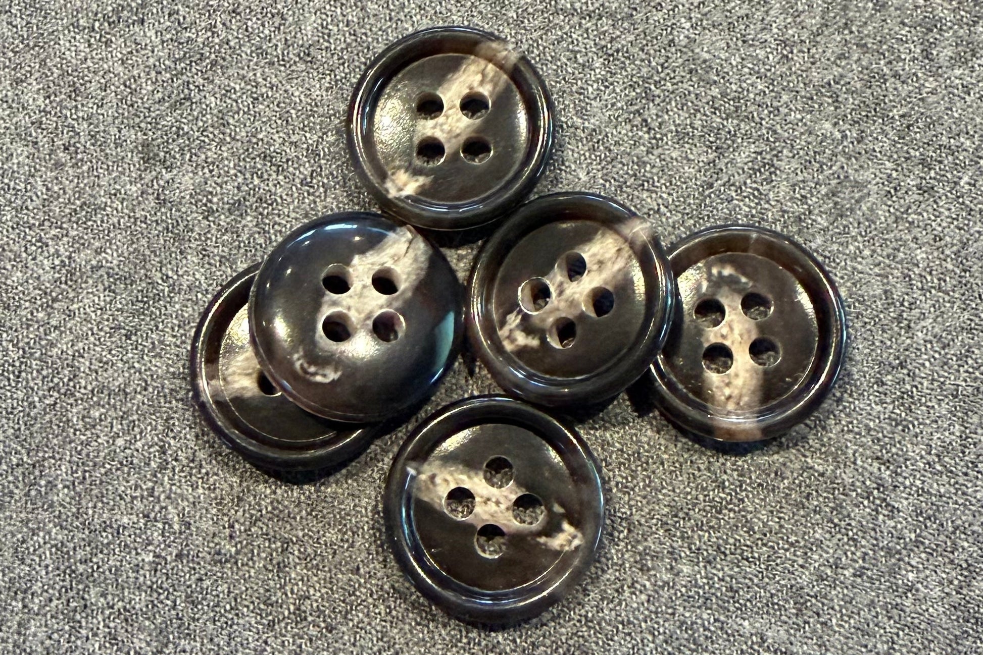 Set of six brown and tan buttons on a textured gray surface