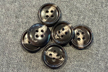 Set of six brown and tan buttons on a textured gray surface