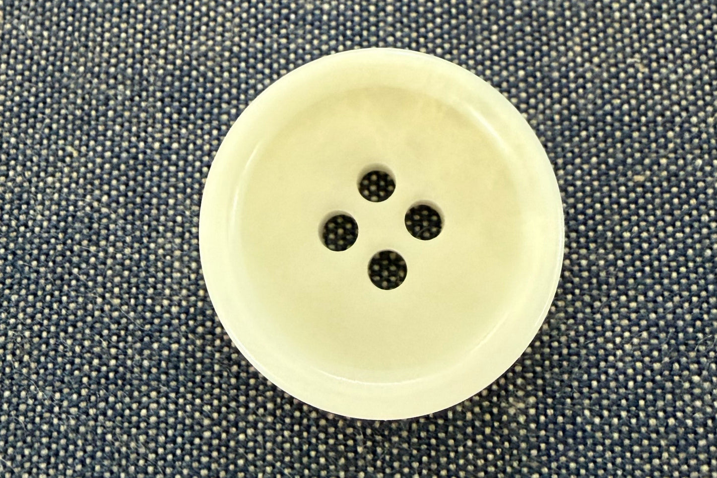 Beige button on a textured gray fabric background