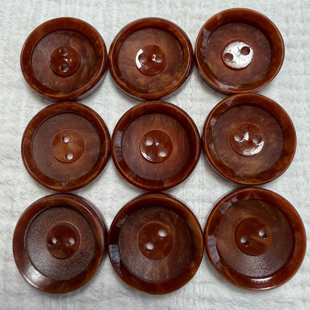 Natural brown casein two-hole buttons with polished and unpolished tiers.