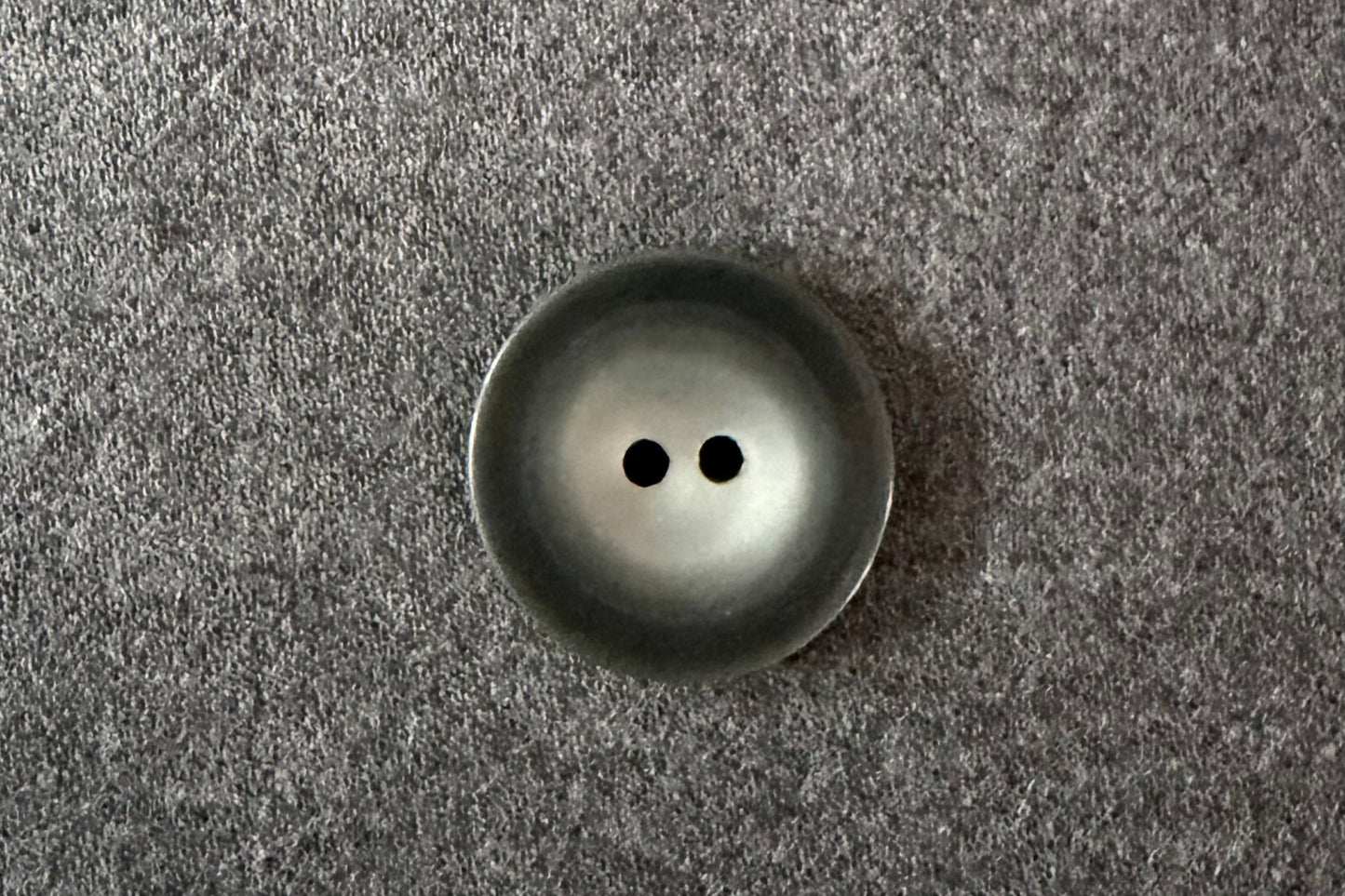 Dark grety button on a textured gray fabric background
