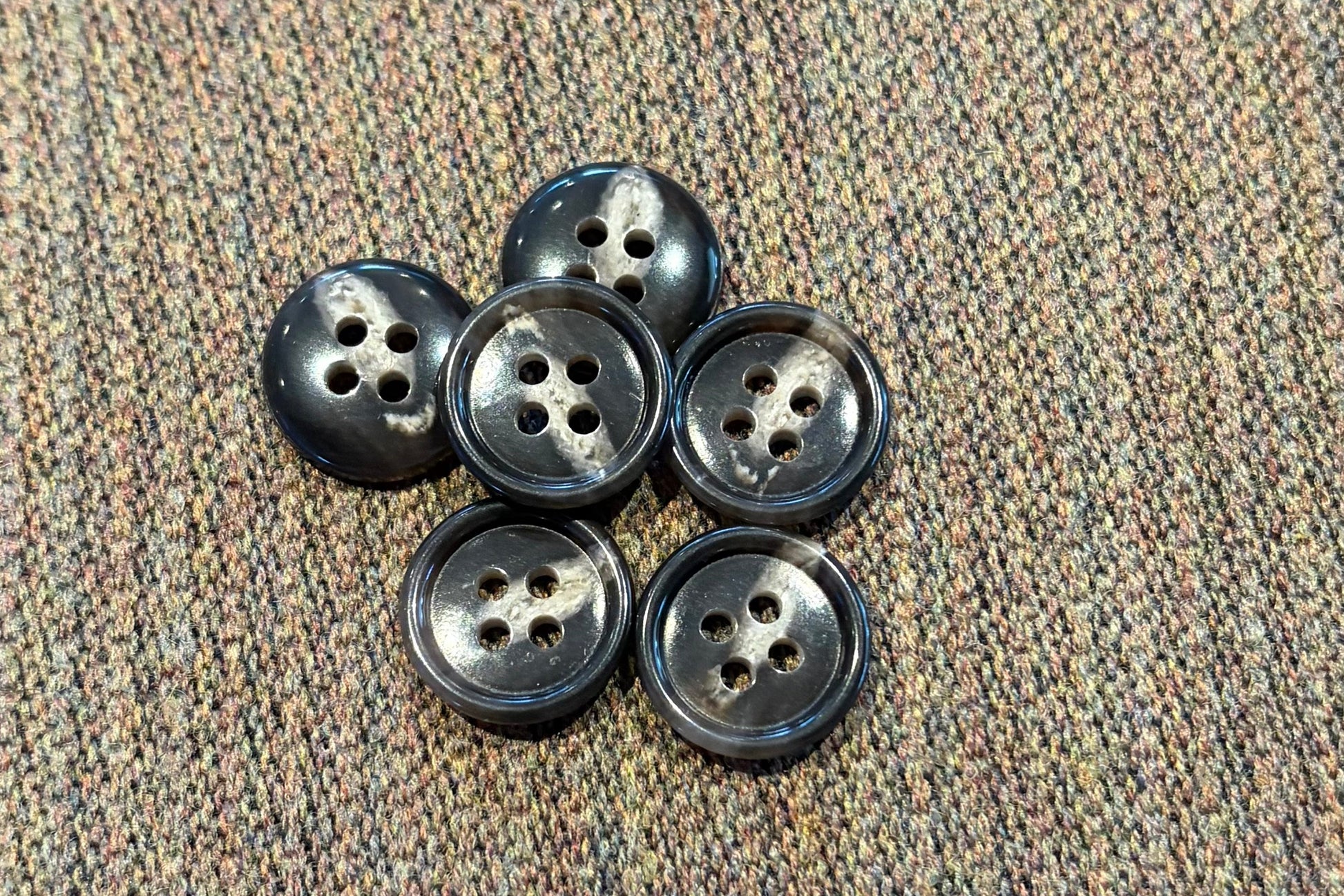 Set of six brown and tan buttons on a textured fabric background