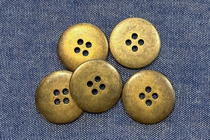 Five bronze buttons on a denim fabric background