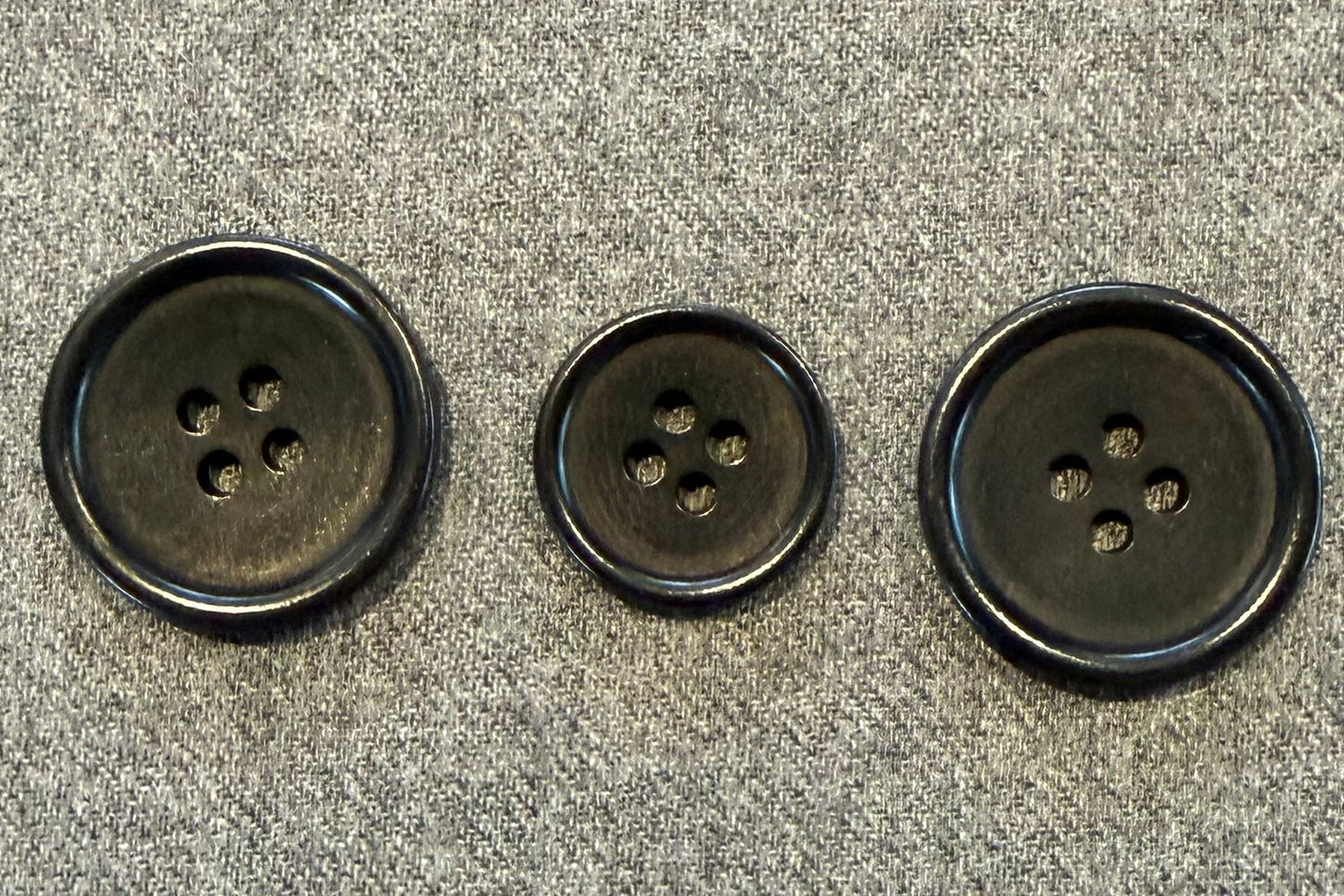 three black buttons on grey fabric
