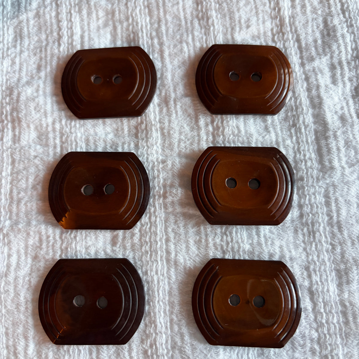 Detail of an oblong brown casein button with a tiered edge.