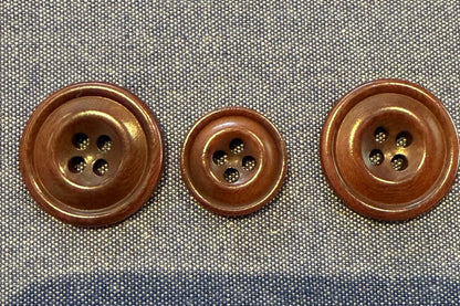 Three brown buttons on a denim fabric background