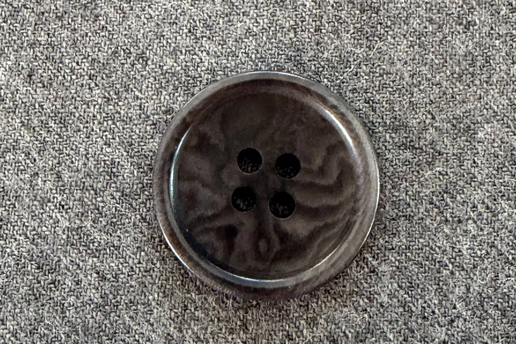 Grey button on a textured gray fabric background