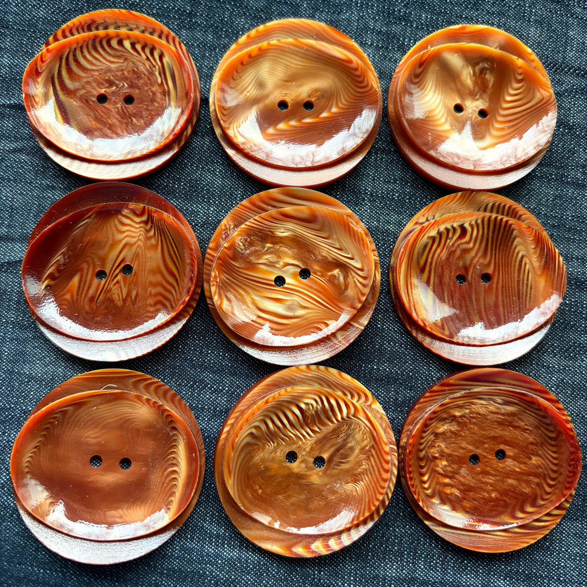 Nine rust swirl statement buttons on denim, each with its own grain pattern.
