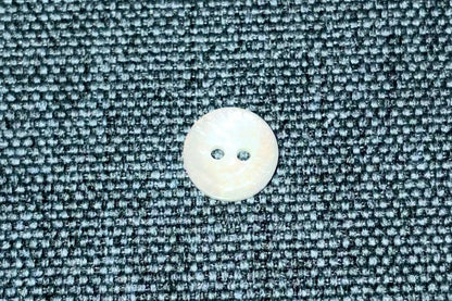 Close-up of a white button on textured blue fabric.