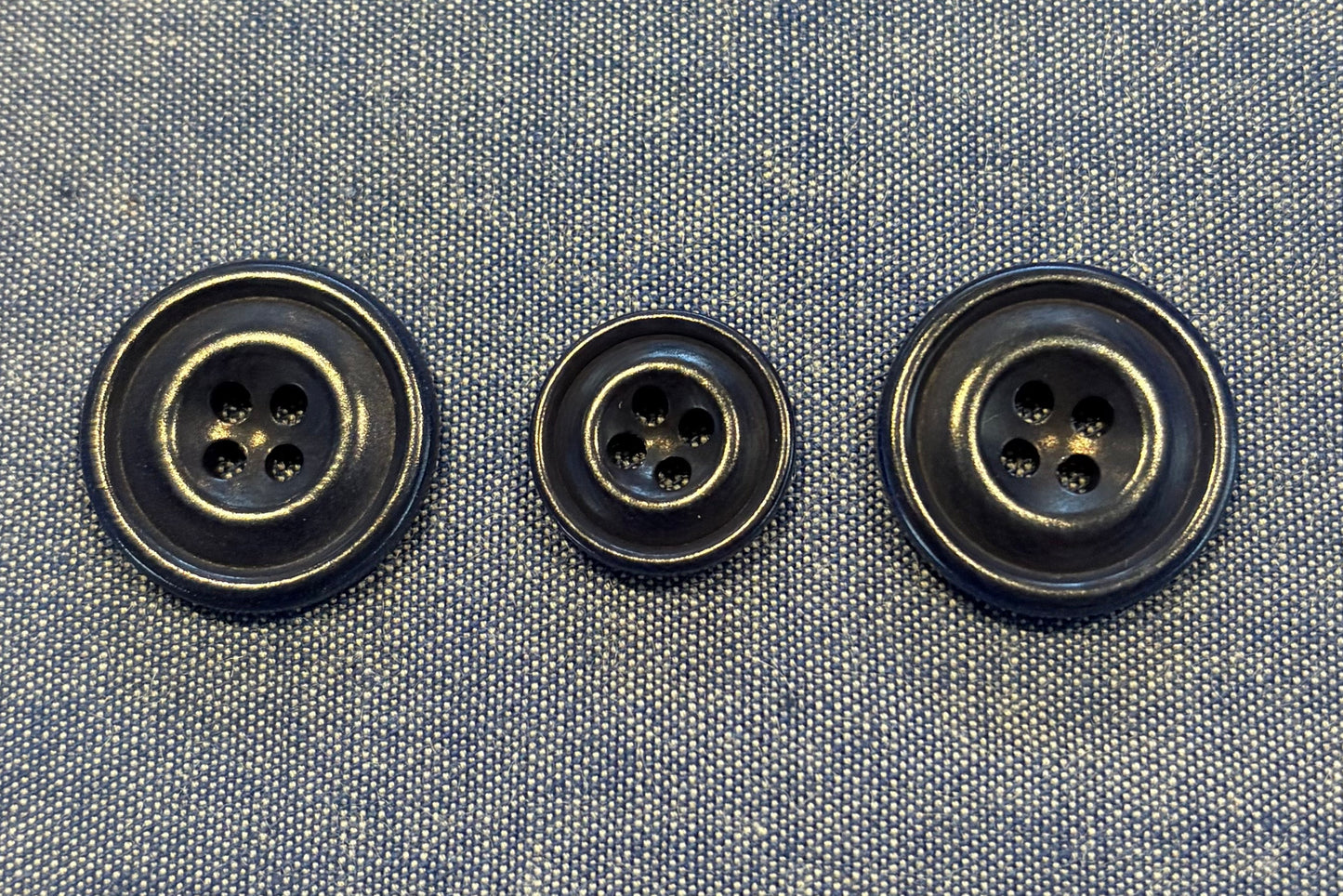 Three blue buttons on a denim fabric background
