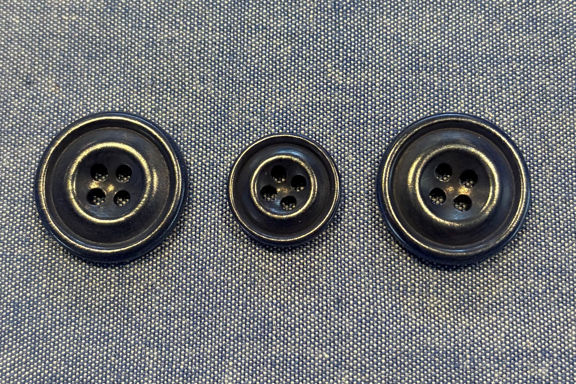 Three blue buttons on a denim fabric background
