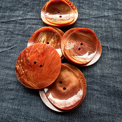Rust swirl statement buttons stacked, showing the flat back and curled front.