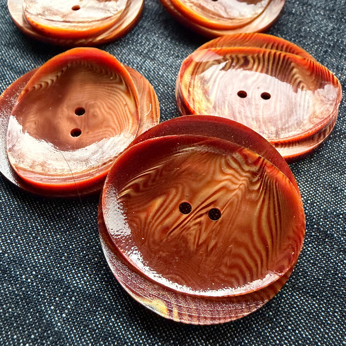 Rust and copper statement buttons with a wood-like swirl and a curled, rolled lip.