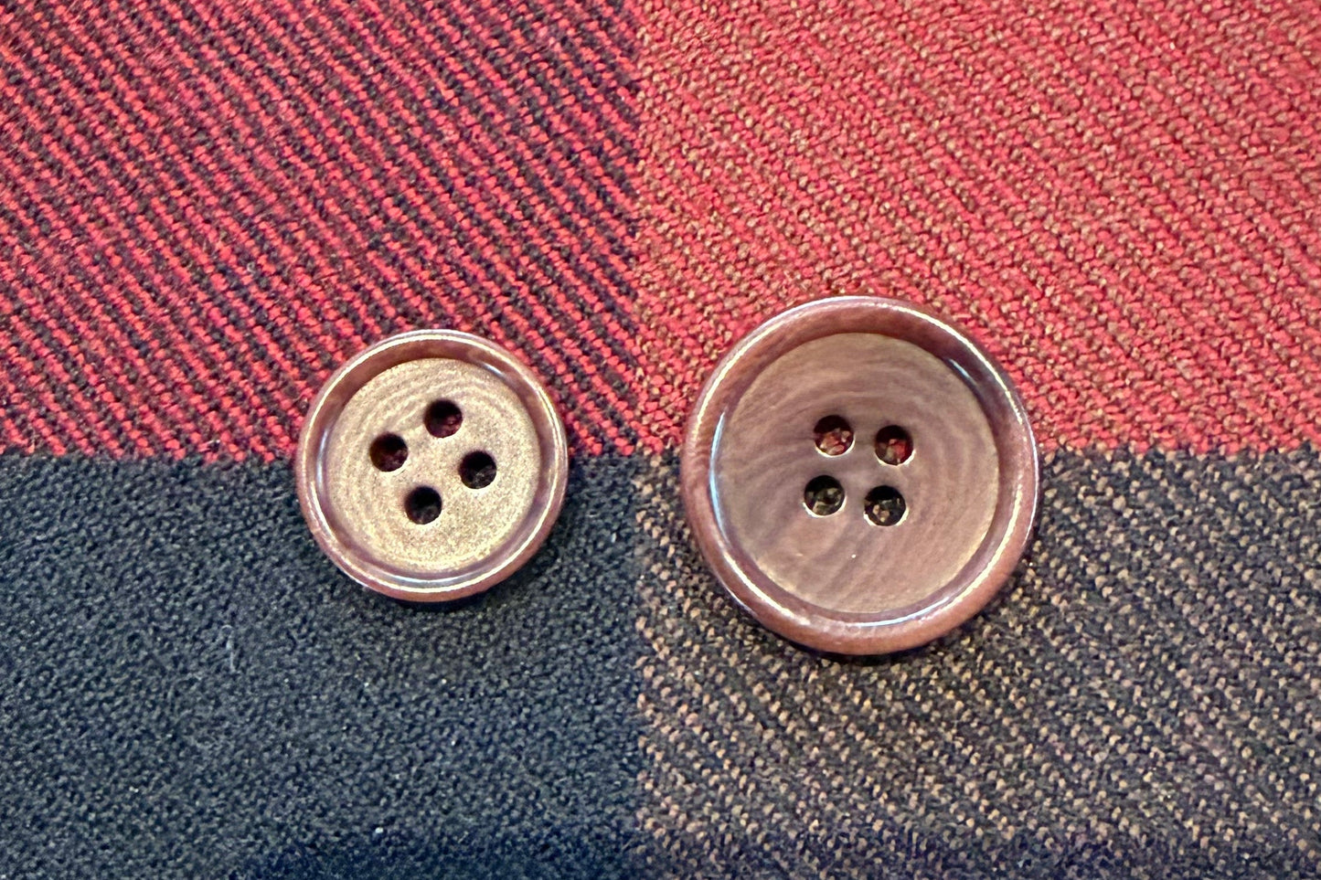 Two brown buttons on plaid fabric.