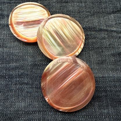 Three rose-gold casein statement buttons on denim, each with a slightly different pattern.