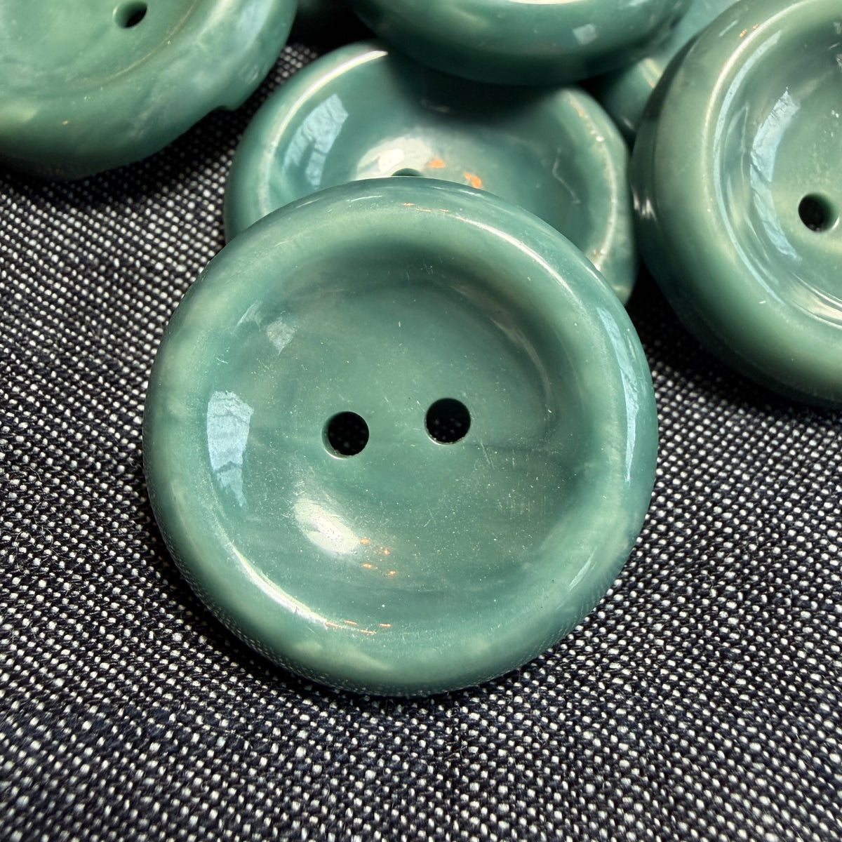 Teal casein concave buttons for a jacket or pants.