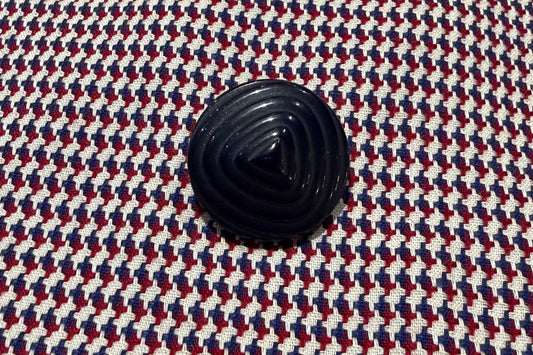 Close-up of a textured fabric with a navy blue button.