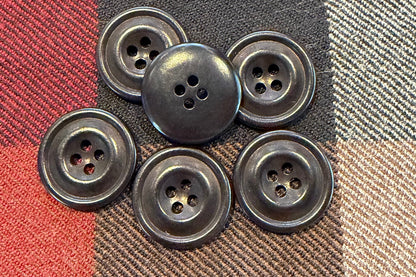 Set of six black buttons on a plaid fabric background