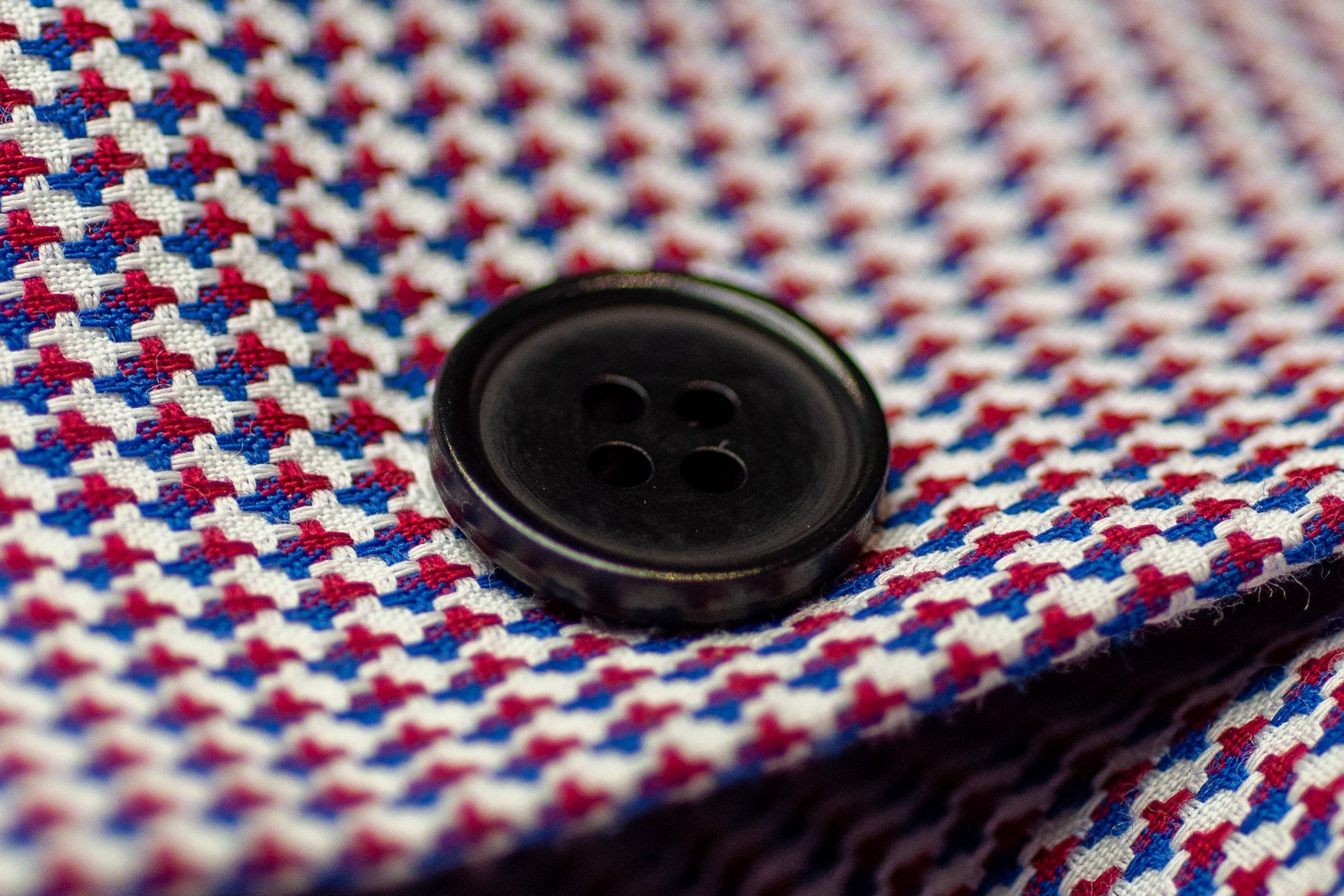 Close-up of a balck button on a red, white, and blue checkered fabric