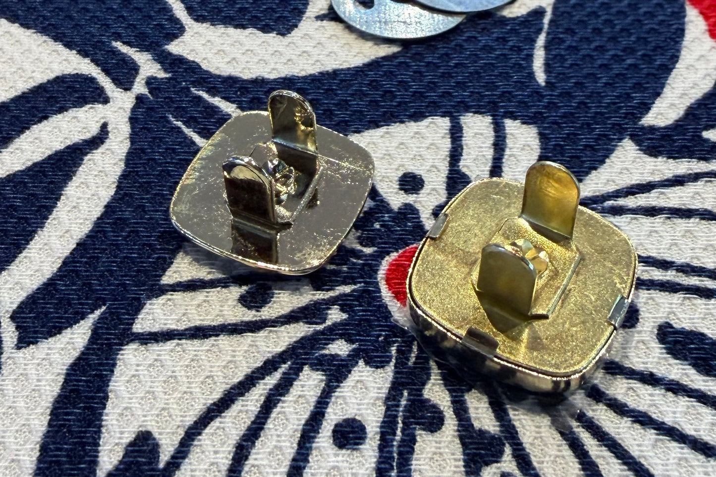 Two parts of a metal snap set on a fabric surface with a floral pattern