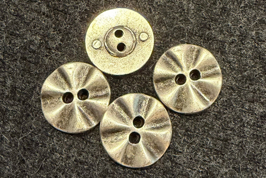 Four metal buttons on a textured dark fabric background