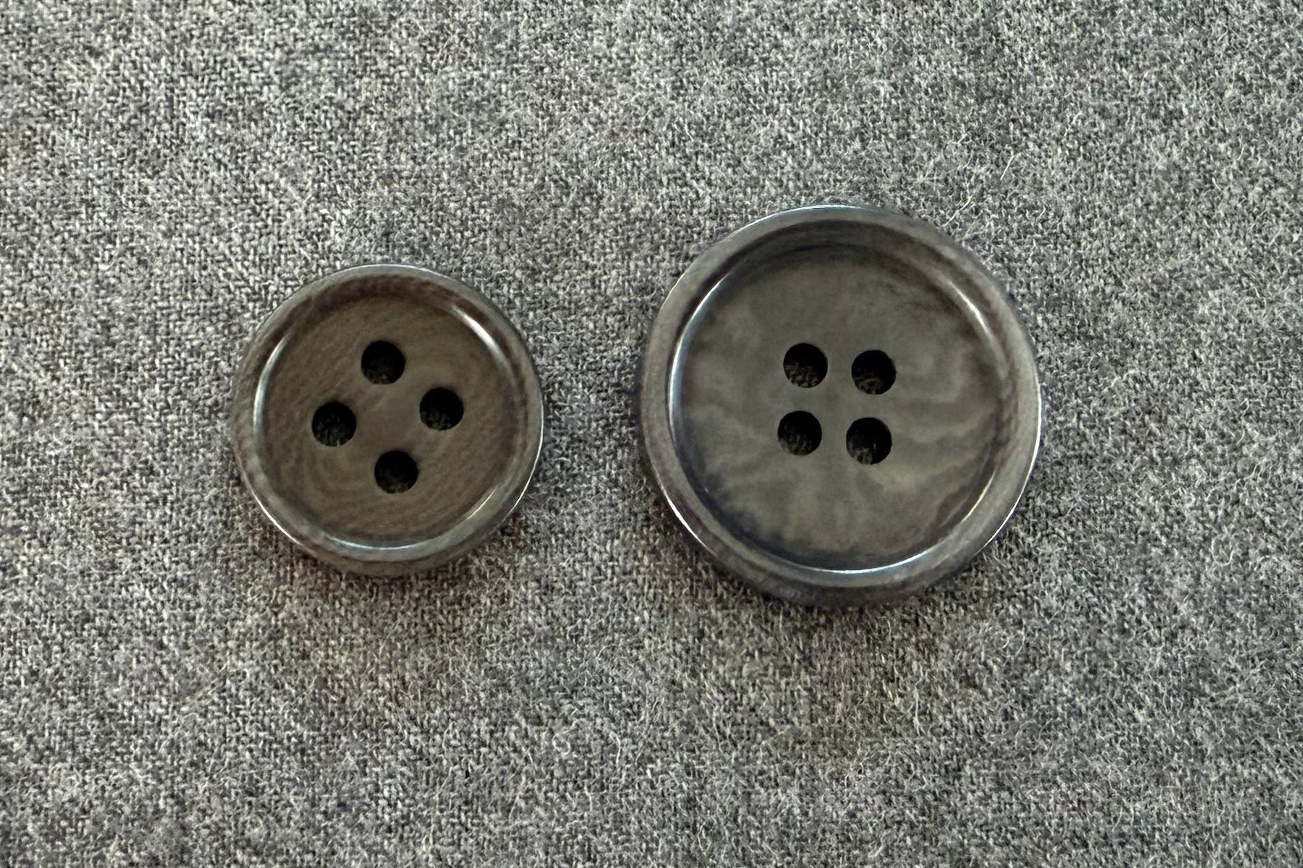 Two grey buttons on a textured gray fabric background