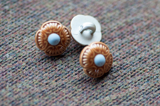 Three decorative floral buttons on a textured fabric background