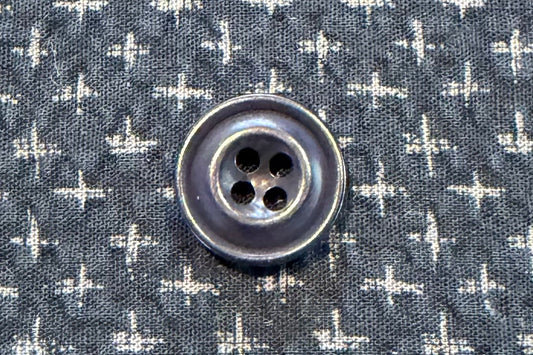 Close-up of a blue button on a shirt with a subtle pattern