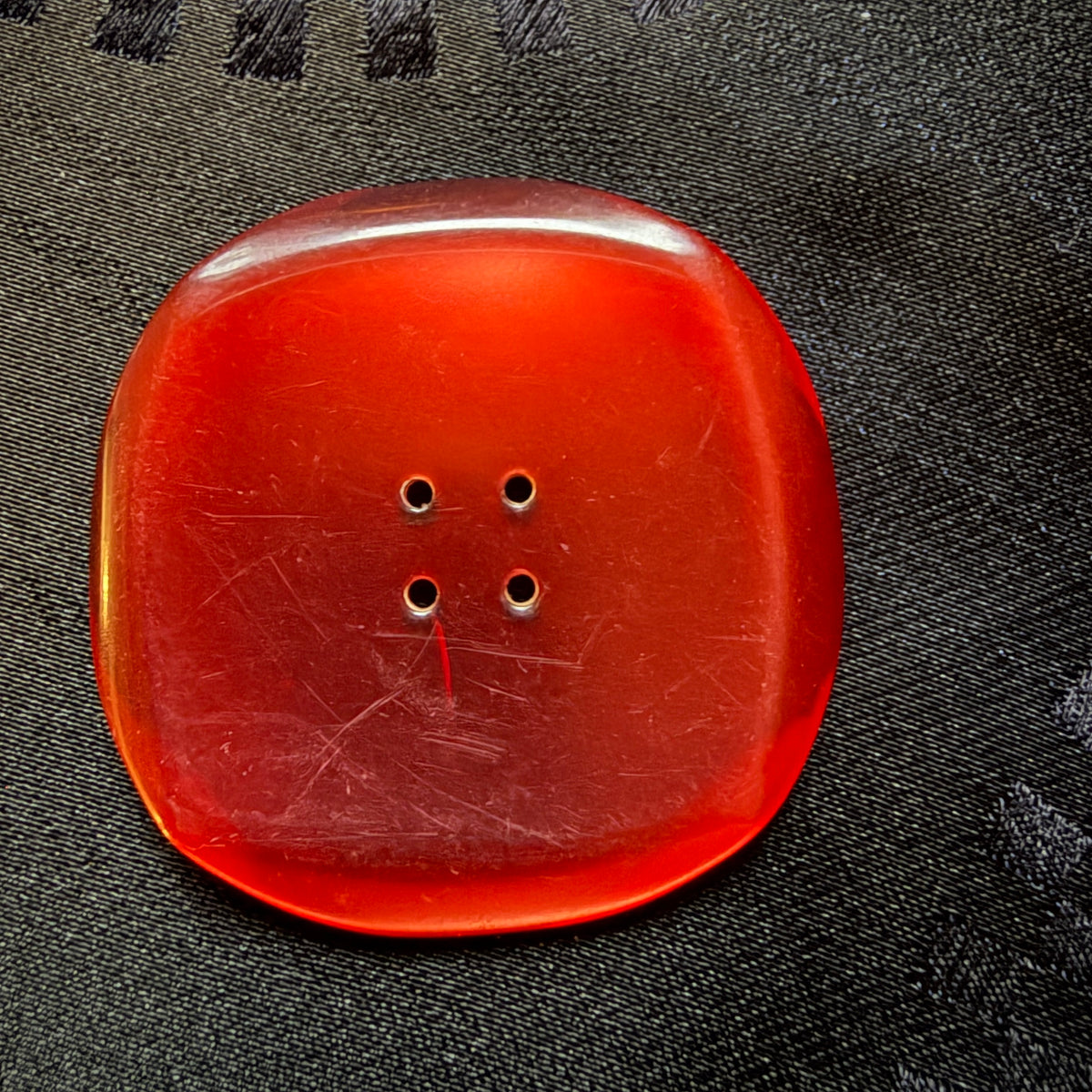 Close-up of a wine-red square glass button showing its glossy face