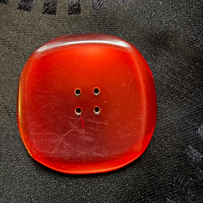 Close-up of a wine-red square glass button showing its glossy face