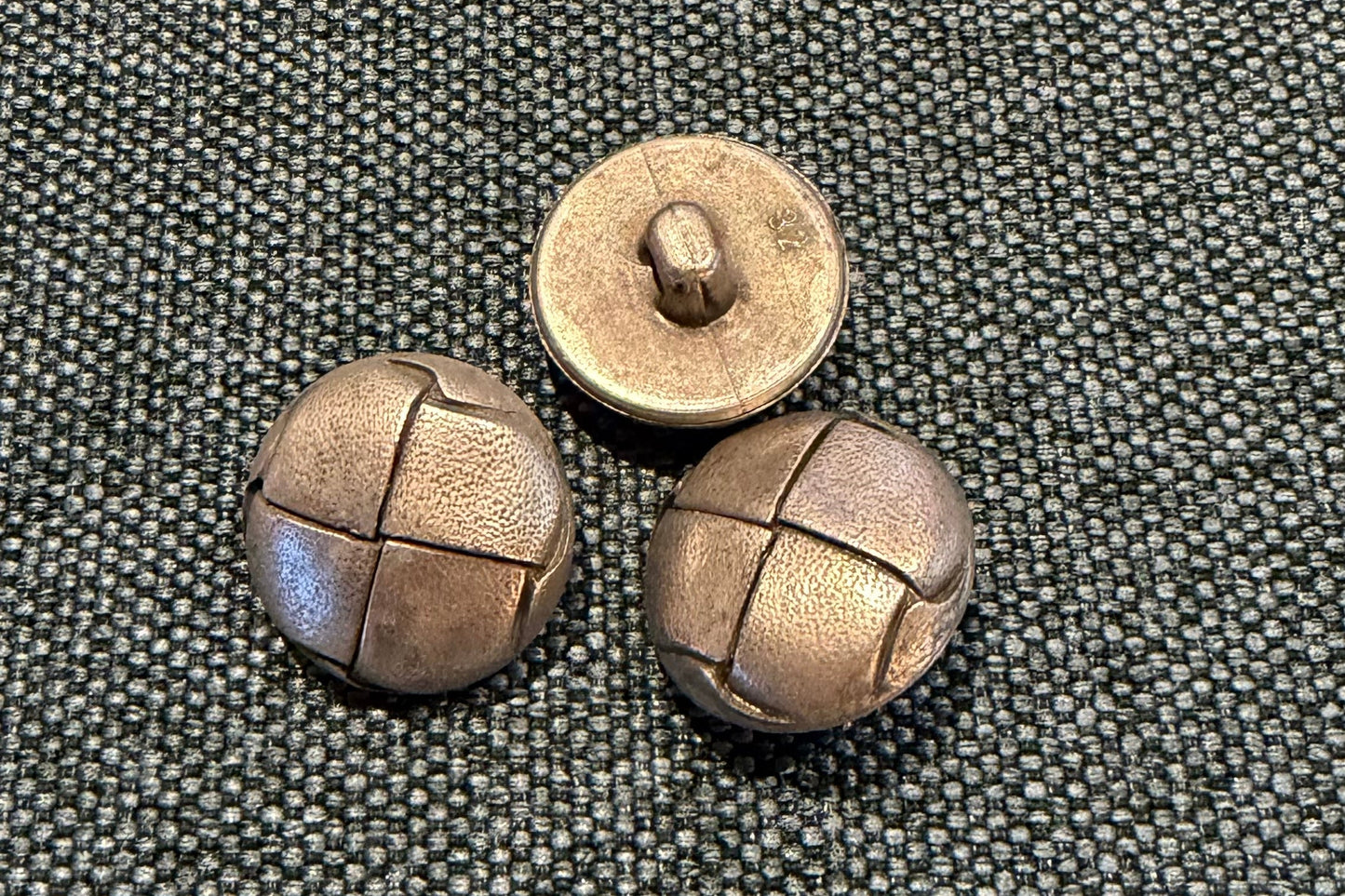 Three silver-coloured buttons on a textured gray surface