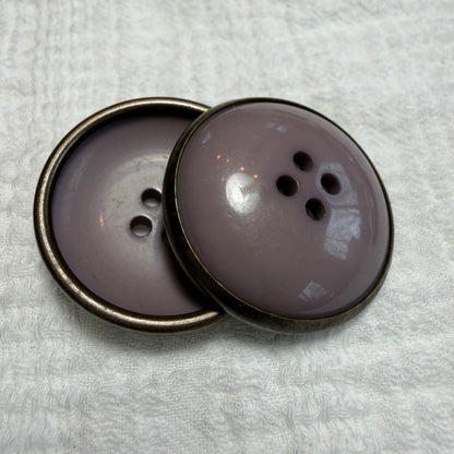 Detail of a mauve concave button with a metal rim.