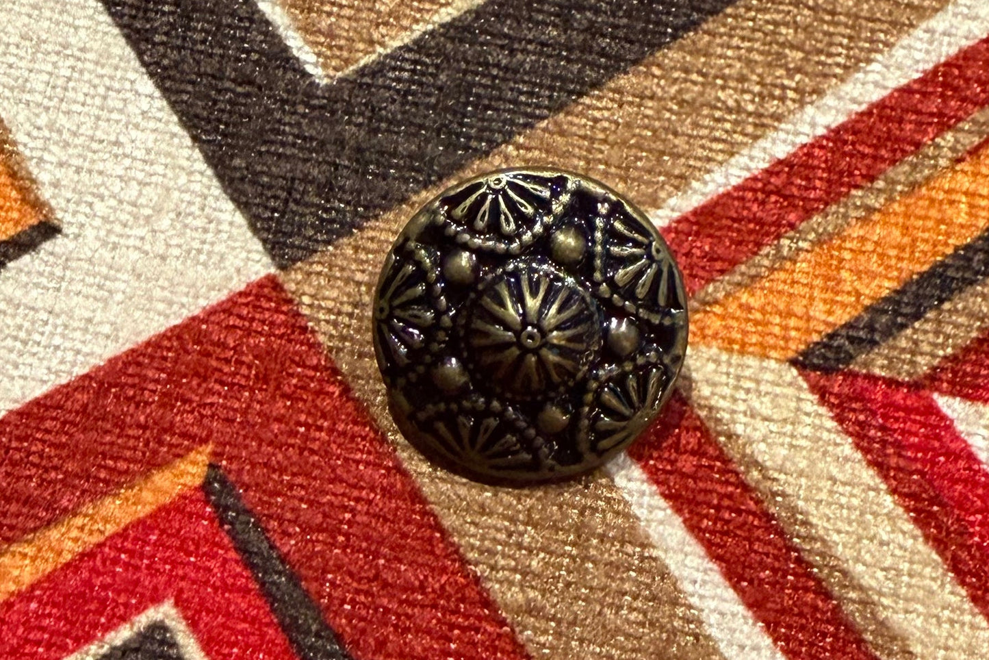 Close-up of a patterned fabric with geometric design and a decorative button on top.