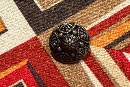Close-up of a patterned fabric with geometric design and a decorative button on top.