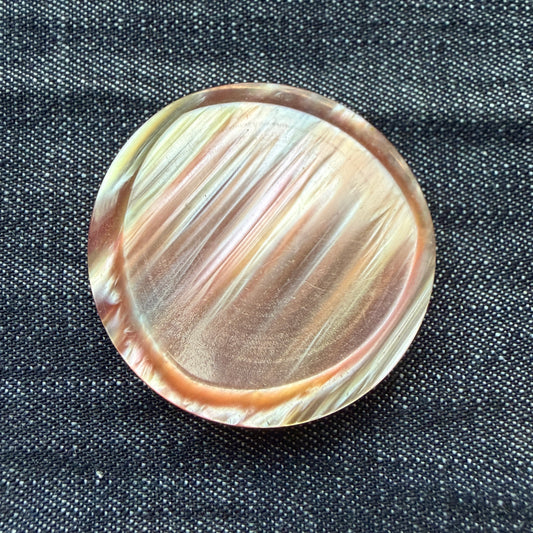 Rose-gold casein statement button with a raised crescent rim and streaks of peach and gold, handmade in Argentina.
