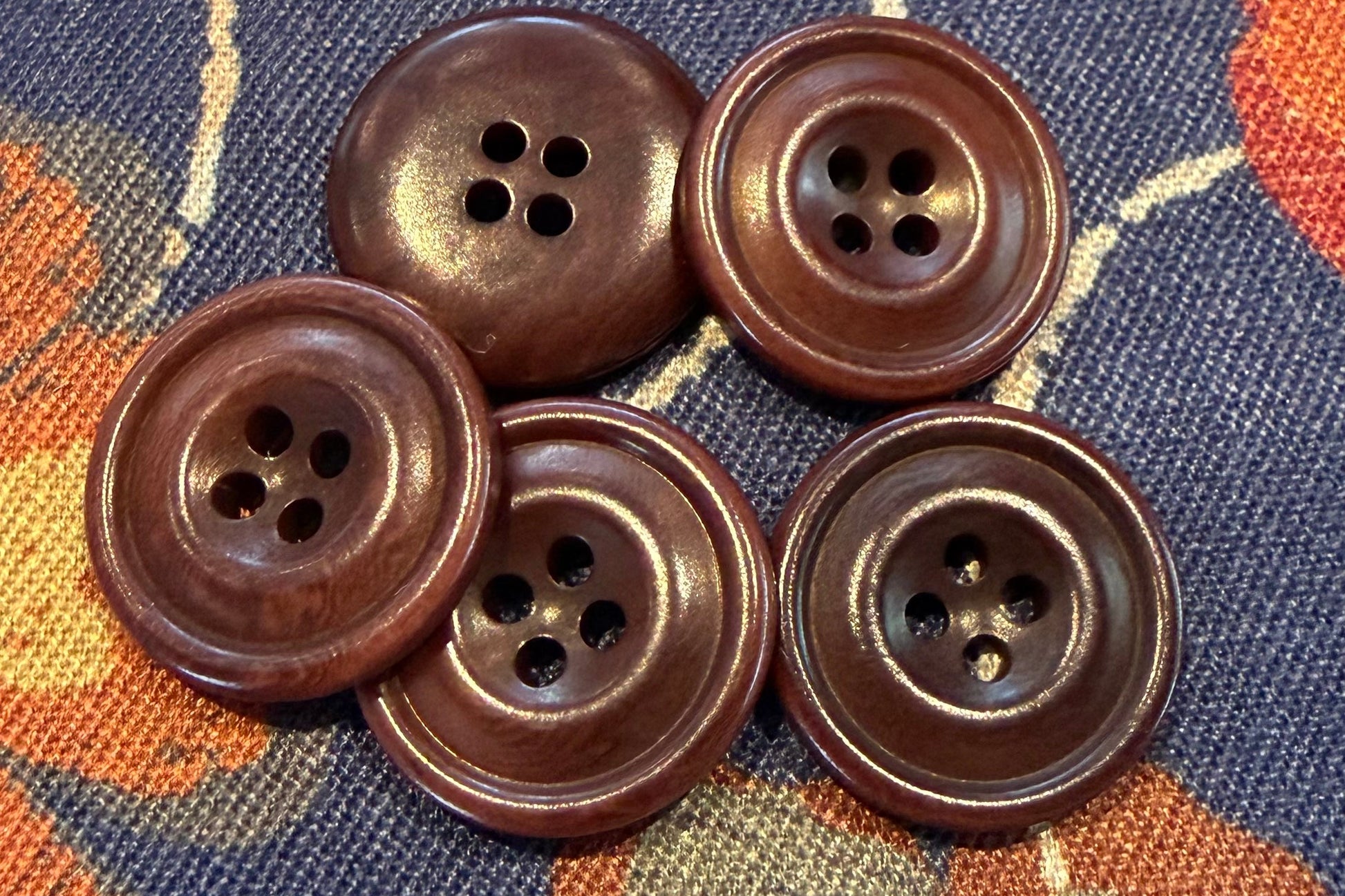 five brown buttons on a fabric background