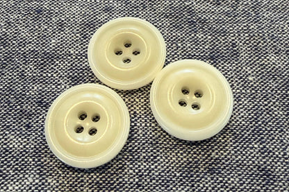 Three white buttons on a textured gray fabric background