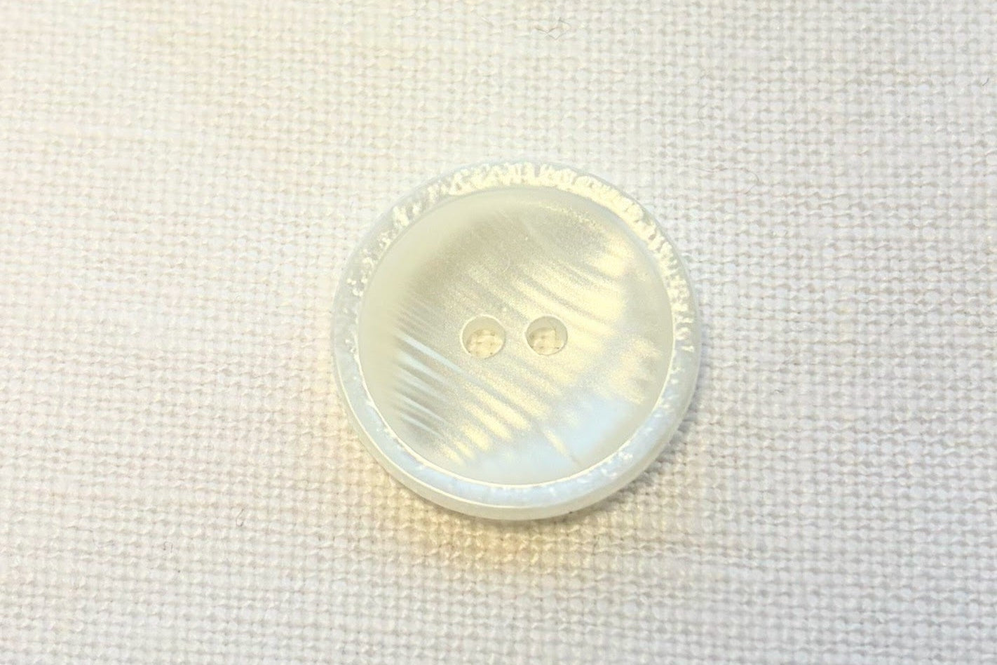 Close-up of a white button on a white fabric background