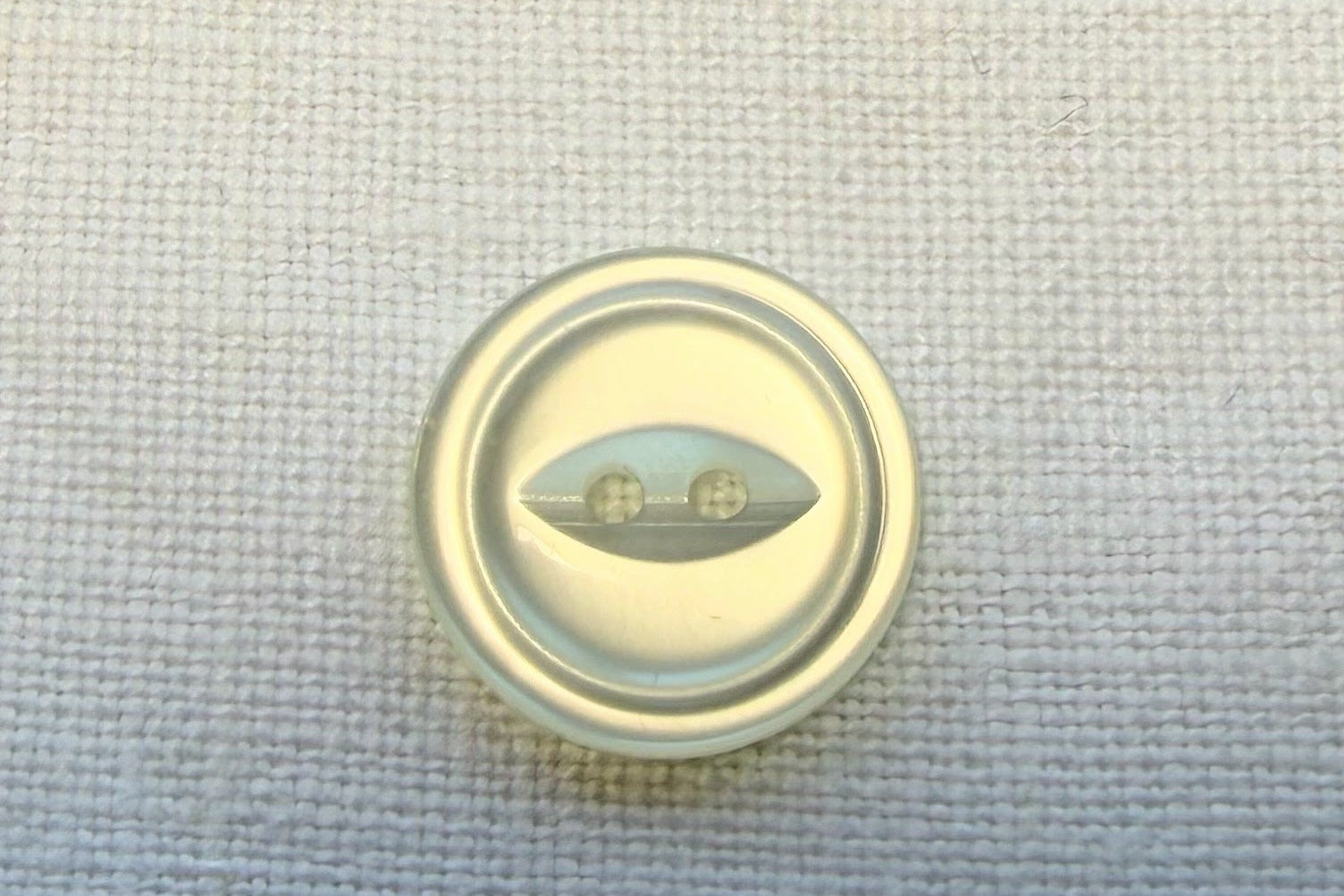 White button on a textured white  fabric background
