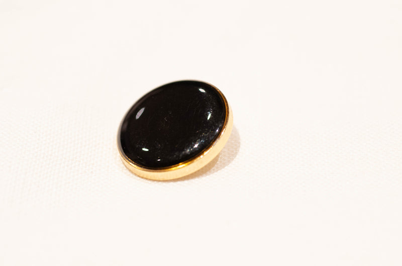 Black button with gold rim on a white background