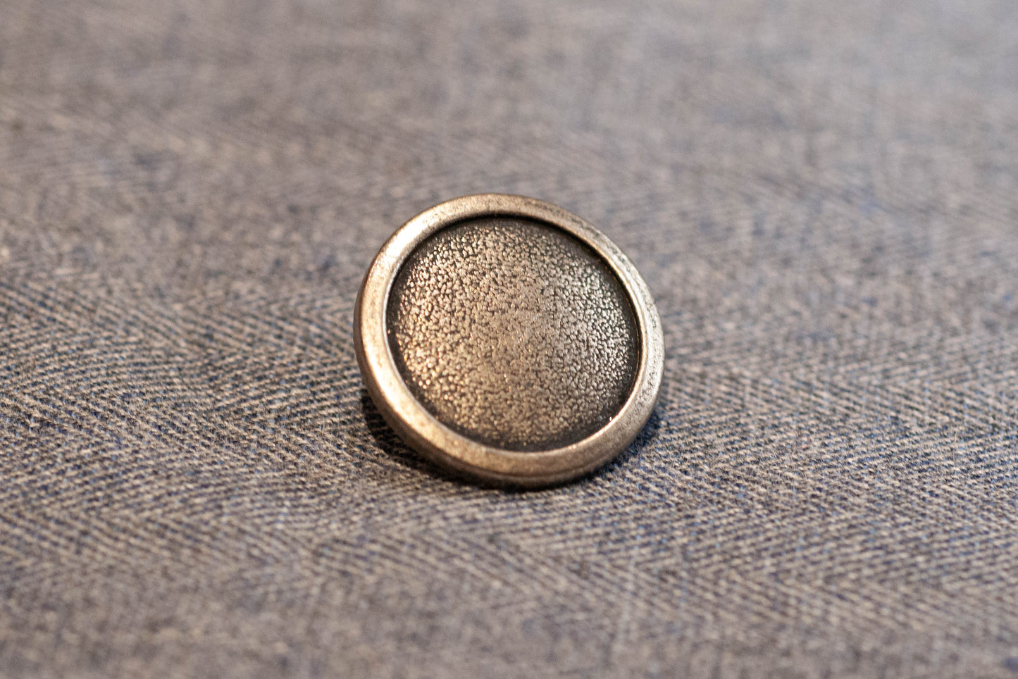 Silver button on a textured fabric background