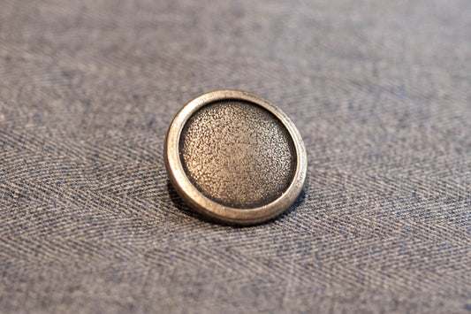 Silver button on a textured fabric background